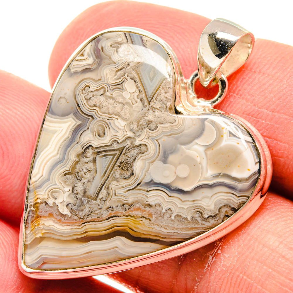 Heart-shaped lace agate pendant close-up in sterling silver with bail, cream and amber bands