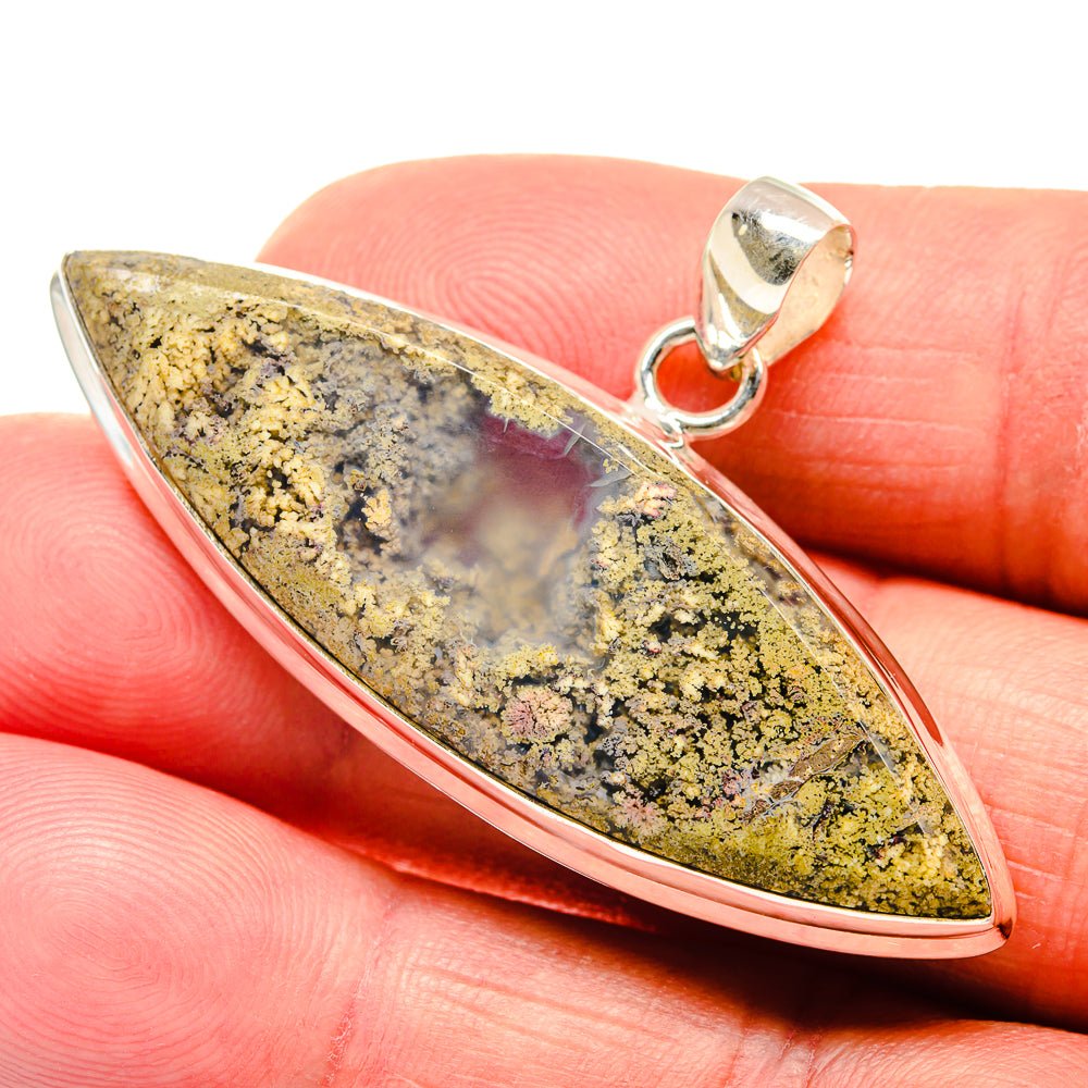 Plume agate pendant closeup on finger; yellow-green marbled stone with silver bezel bail