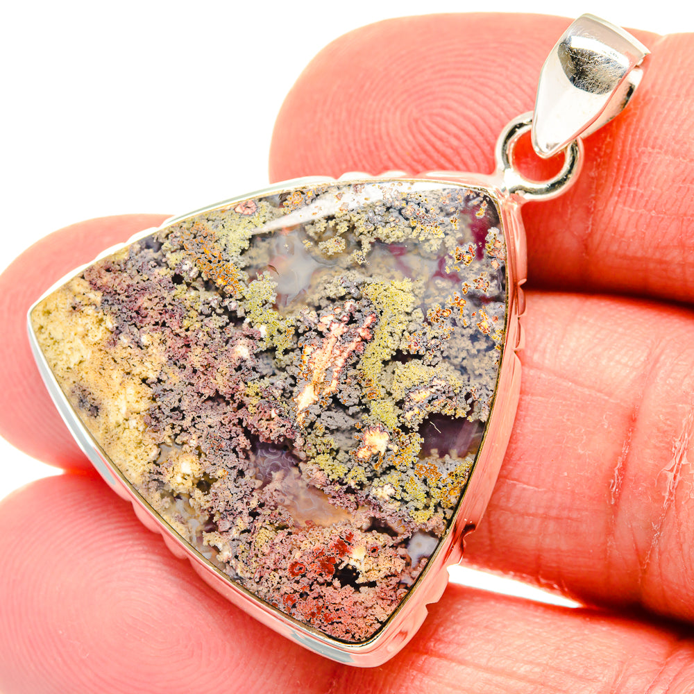 Close-up triangular plume agate pendant with silver bail, purple-gray and golden flecks