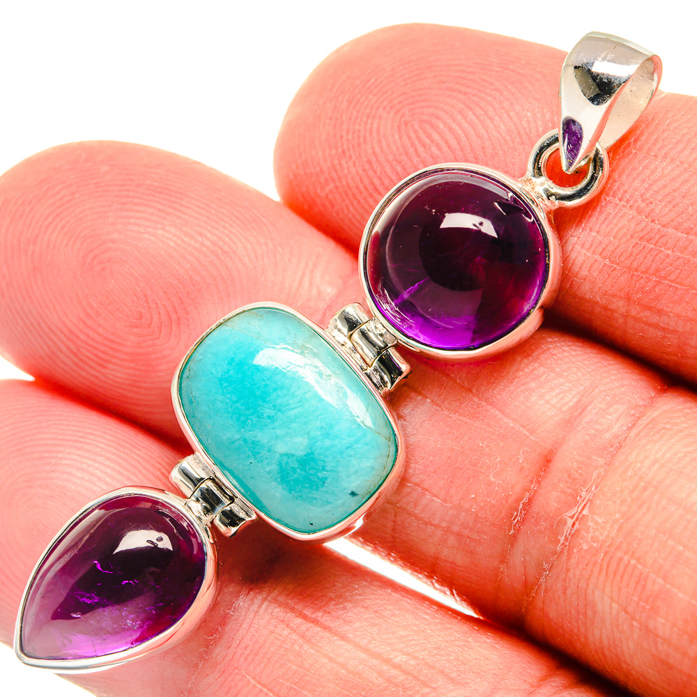Oval amethyst and larimar stones in a sterling silver pendant, close-up on finger