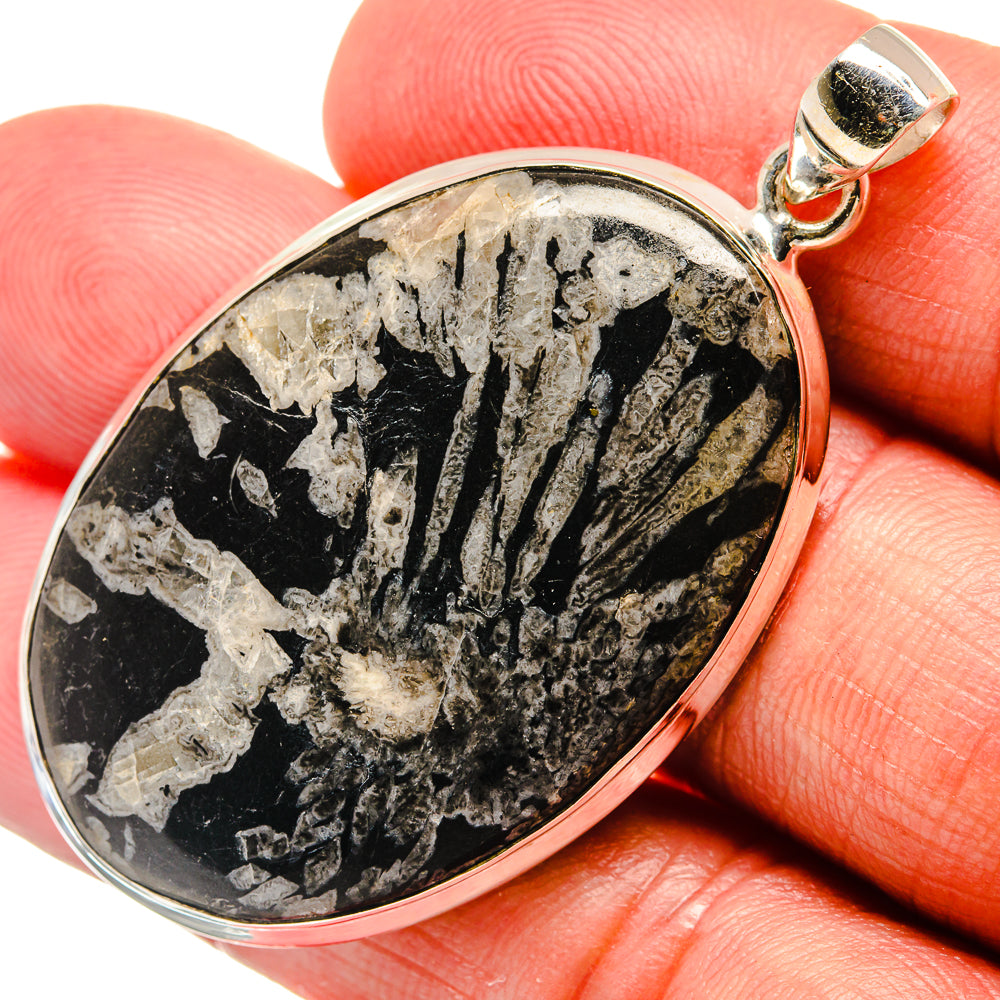 Oval black stone pendant in sterling silver bezel with loop bail, visible stone texture