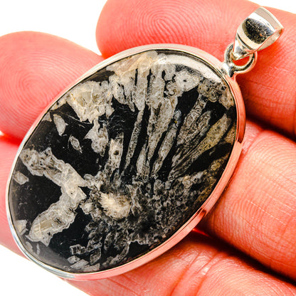 Oval black stone pendant in sterling silver bezel with loop bail, visible stone texture