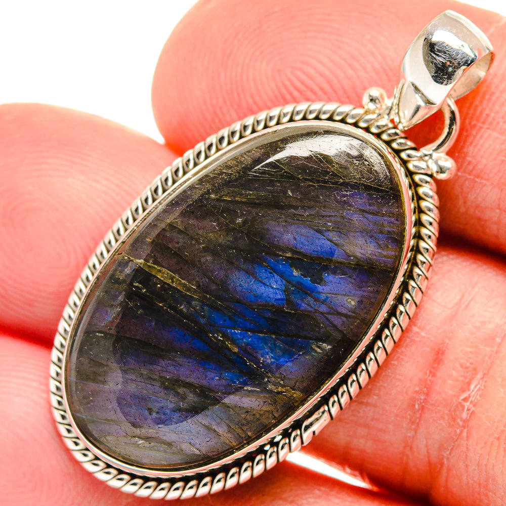 Oval labradorite pendant close-up in 925 sterling silver setting, dark with blue iridescence.