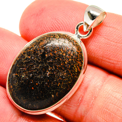 Sterling silver dinosaur bone pendant close-up, oval black stone with amber mottling bezel
