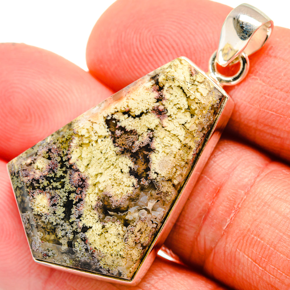 Plume agate pendant close-up on silver bail, yellow, black, and gray marbled rectangle