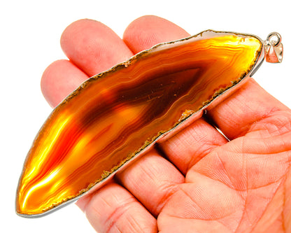 Sterling silver bail red geode slice pendant on hand, bright orange and yellow bands