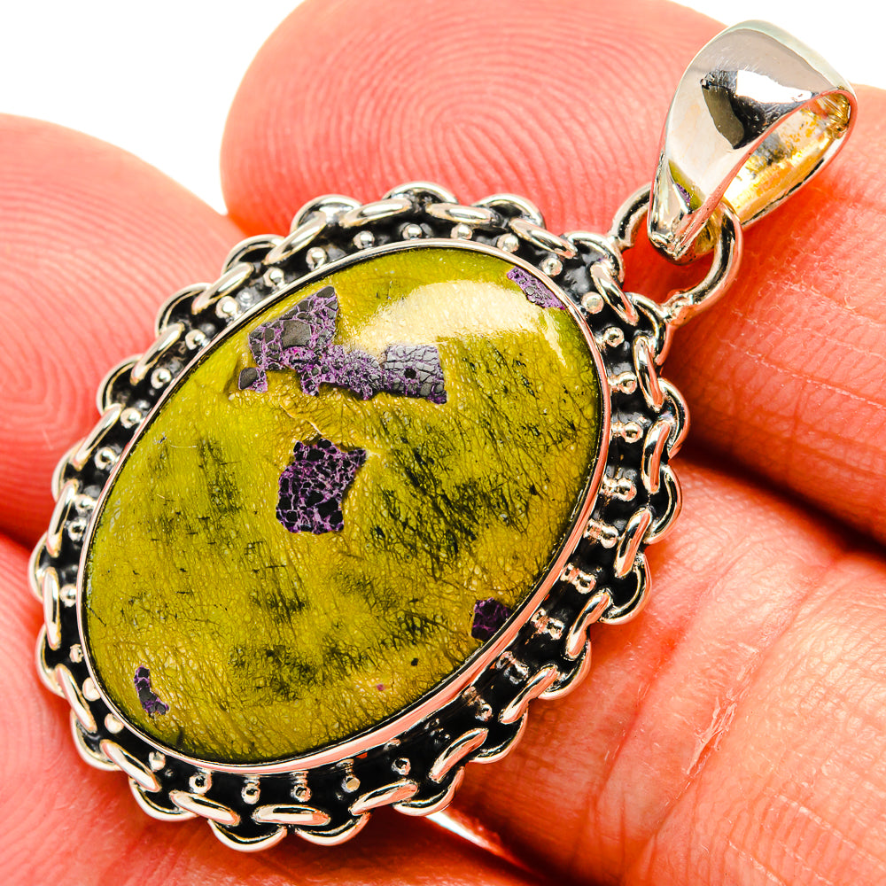 Oval sterling silver pendant close-up with green stone and purple accents, silver bail