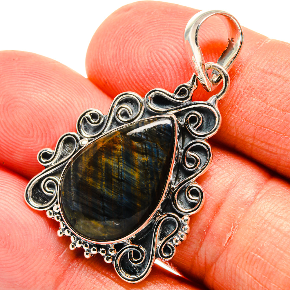 Labradorite pendant close-up, teardrop stone with blue-gold shimmer and silver filigree.