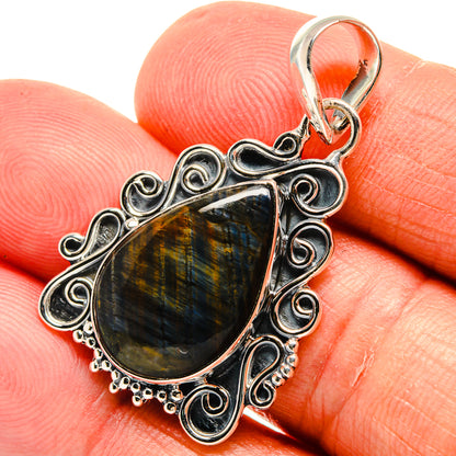 Labradorite pendant close-up, teardrop stone with blue-gold shimmer and silver filigree.