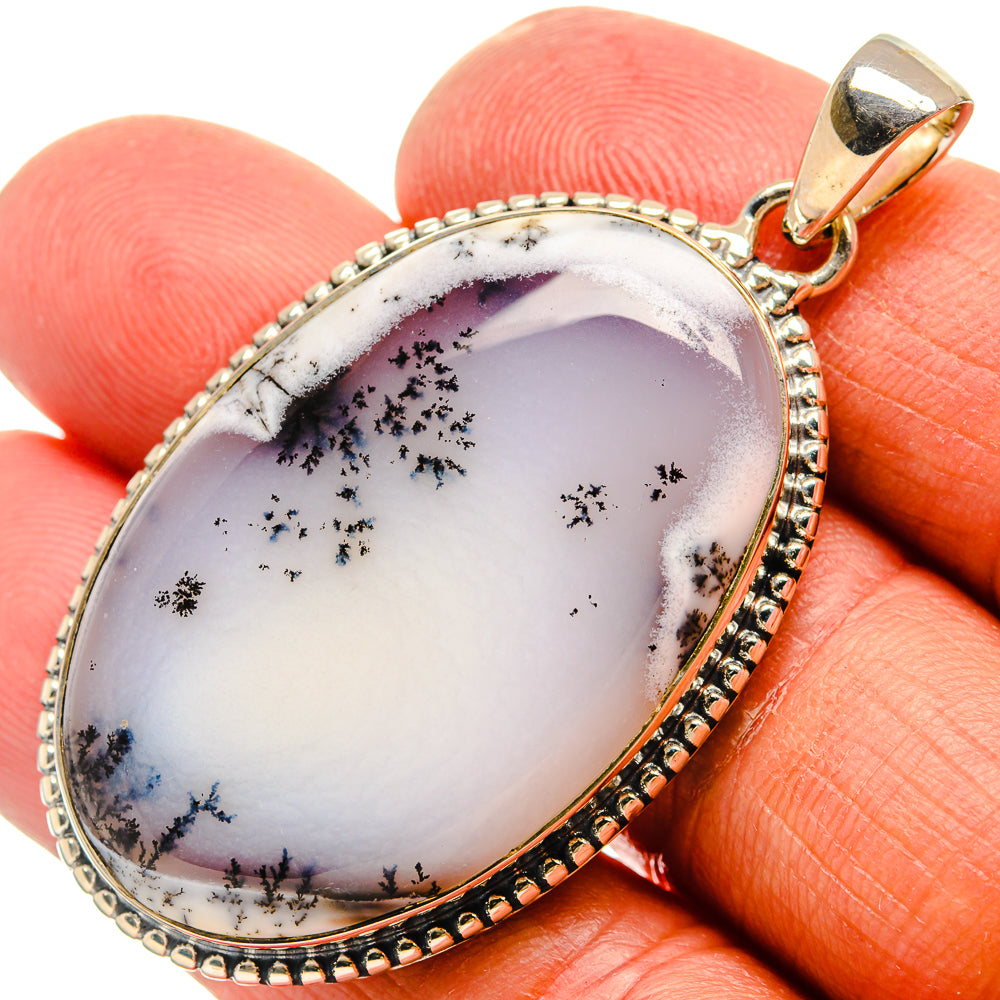 Oval opal pendant with black dendrite inclusions, gold-tone frame and bail