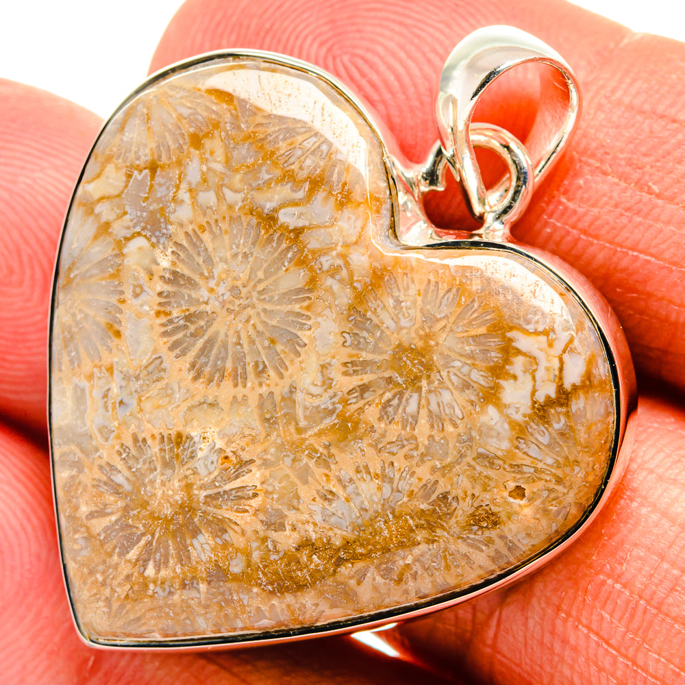 Heart-shaped fossil coral pendant close-up, orange stone with silver bail