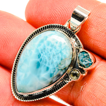 Close-up 925 sterling silver pendant with oval larimar-blue stone, green cabochon, and crystal