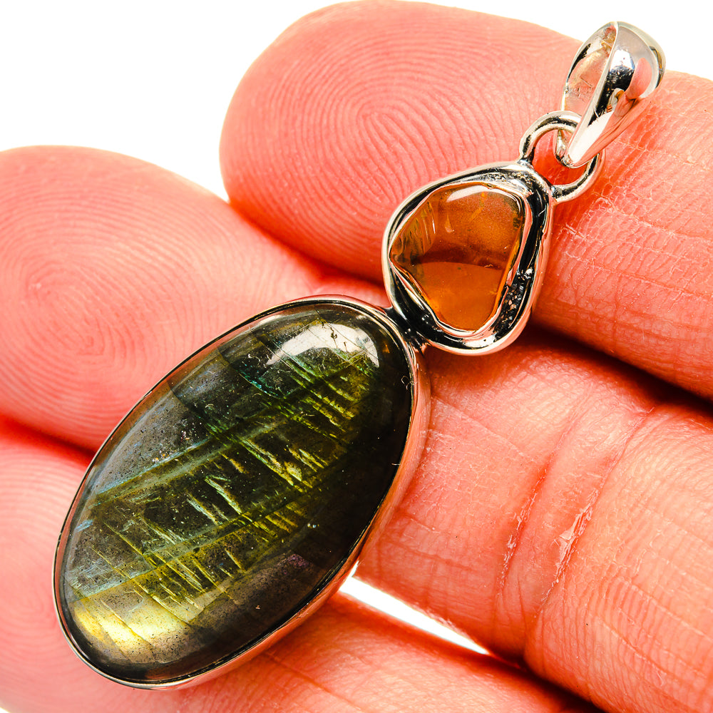Oval labradorite and orange carnelian pendant close-up on fingers, 925 sterling silver