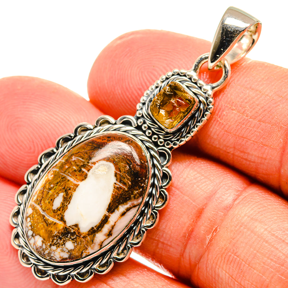 Oval brown and white stone pendant with ornate silver frame and gold-tone bail