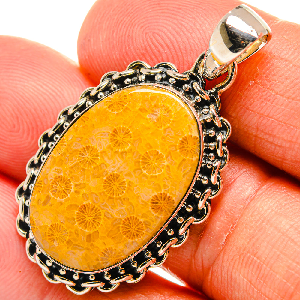 Oval coral pendant in golden orange with ornate silver-tone bezel and bail.