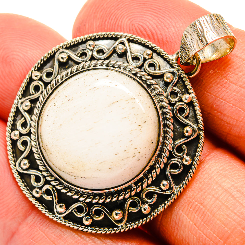 Round 925 sterling silver pendant with detailed filigree frame and pale cabochon stone