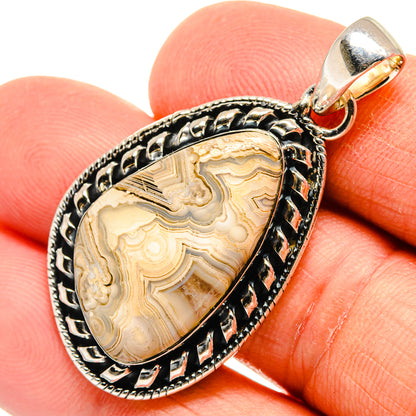Lace agate pendant in oval sterling silver setting with gold-toned bail