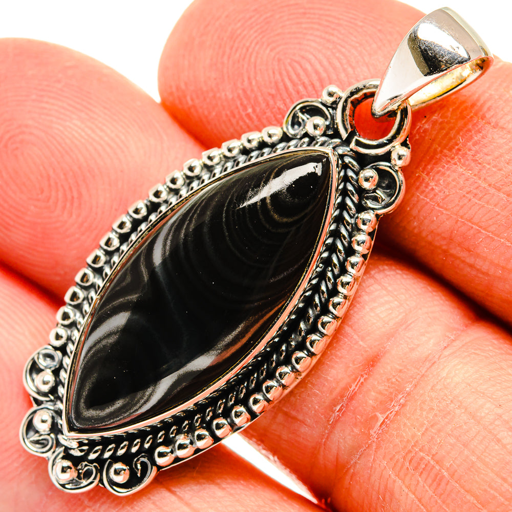 Oval black stone pendant with decorative sterling silver frame and top bail, close-up
