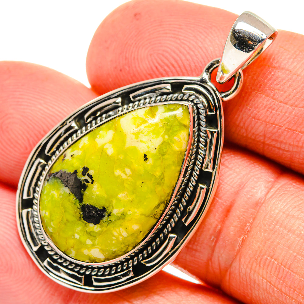 Teardrop green opal pendant with ornate silver bezel and bail, shown in hand