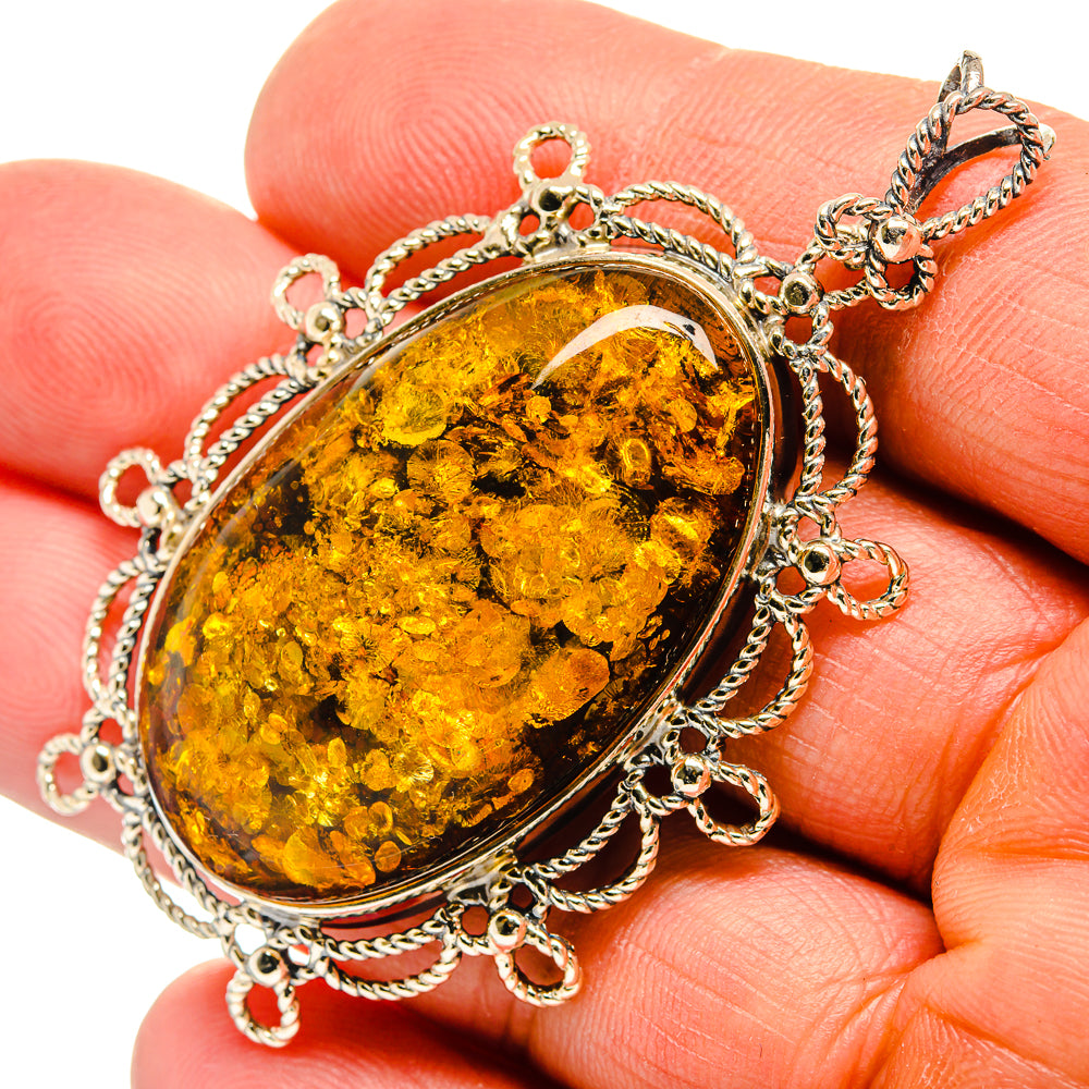 Oval Baltic amber cabochon pendant in silver bezel with chain-link frame and bail