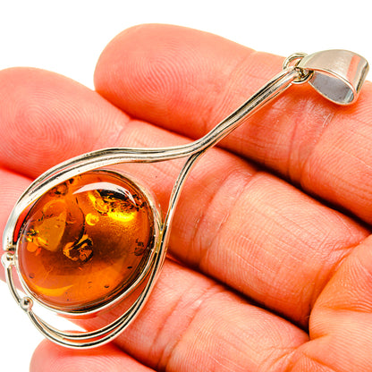 Sterling silver amber pendant with round cabochon and wavy swirl frame