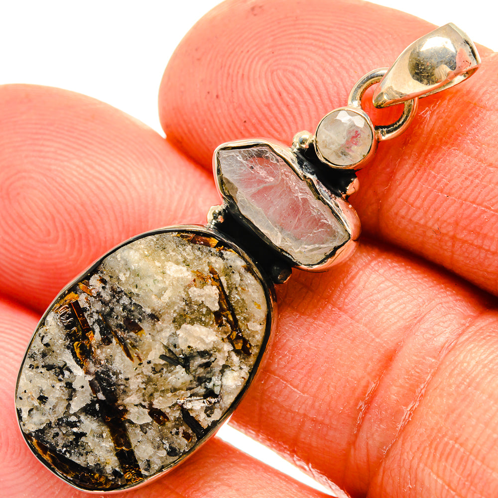 Silver-tone pendant close-up with speckled oval gemstone and rose-pink rough stone.