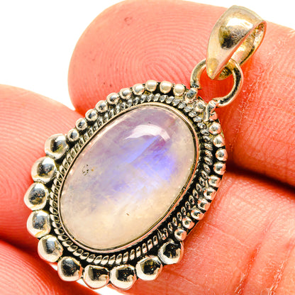 Oval moonstone pendant in sterling silver with ornate bezel and bail, close-up.