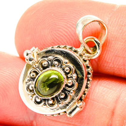 Silver peridot pendant close-up with green oval stone and scrolling filigree bezel