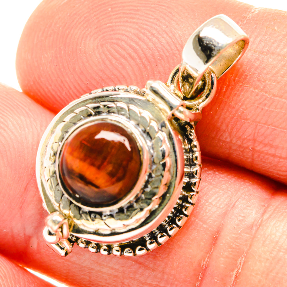 Close-up red tiger eye pendant with textured silver frame and gold-tone bail