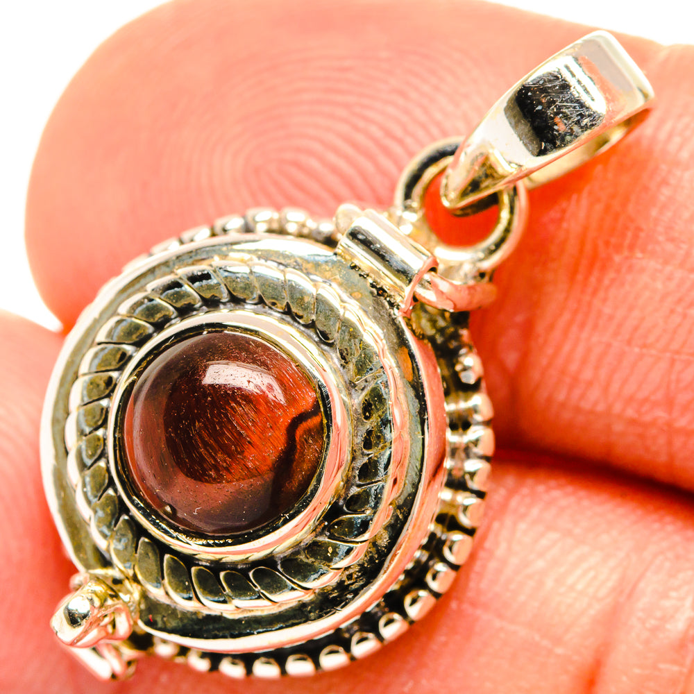 Tiger eye pendant close-up: red-brown cabochon in detailed silver surround with bail