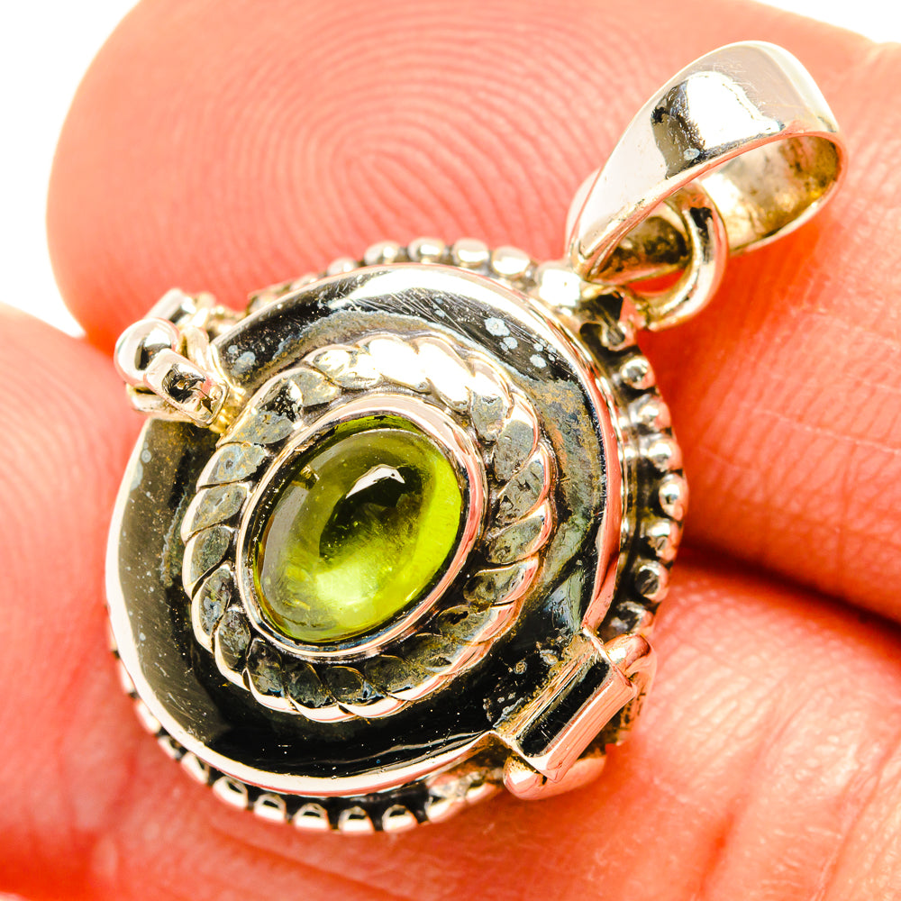 Close-up sterling silver pendant with round green peridot gemstone and decorative side bezels