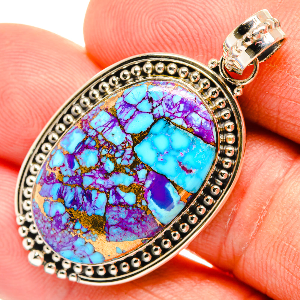 Oval turquoise and purple stone pendant with ornate silver bezel and clasp bail