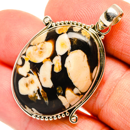 Oval jasper pendant in sterling silver bezel with black background and cream inclusions