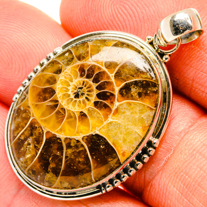 Close-up round sterling silver fossil pendant with golden amber pattern and bail