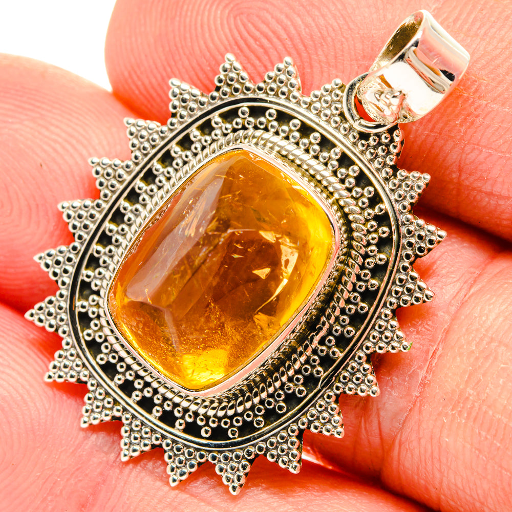 Citrine sugarloaf pendant in dark silver sunburst bezel, set on fingertip