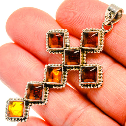 Amber square cross pendant close-up on hand, silver-tone settings with top bail loop
