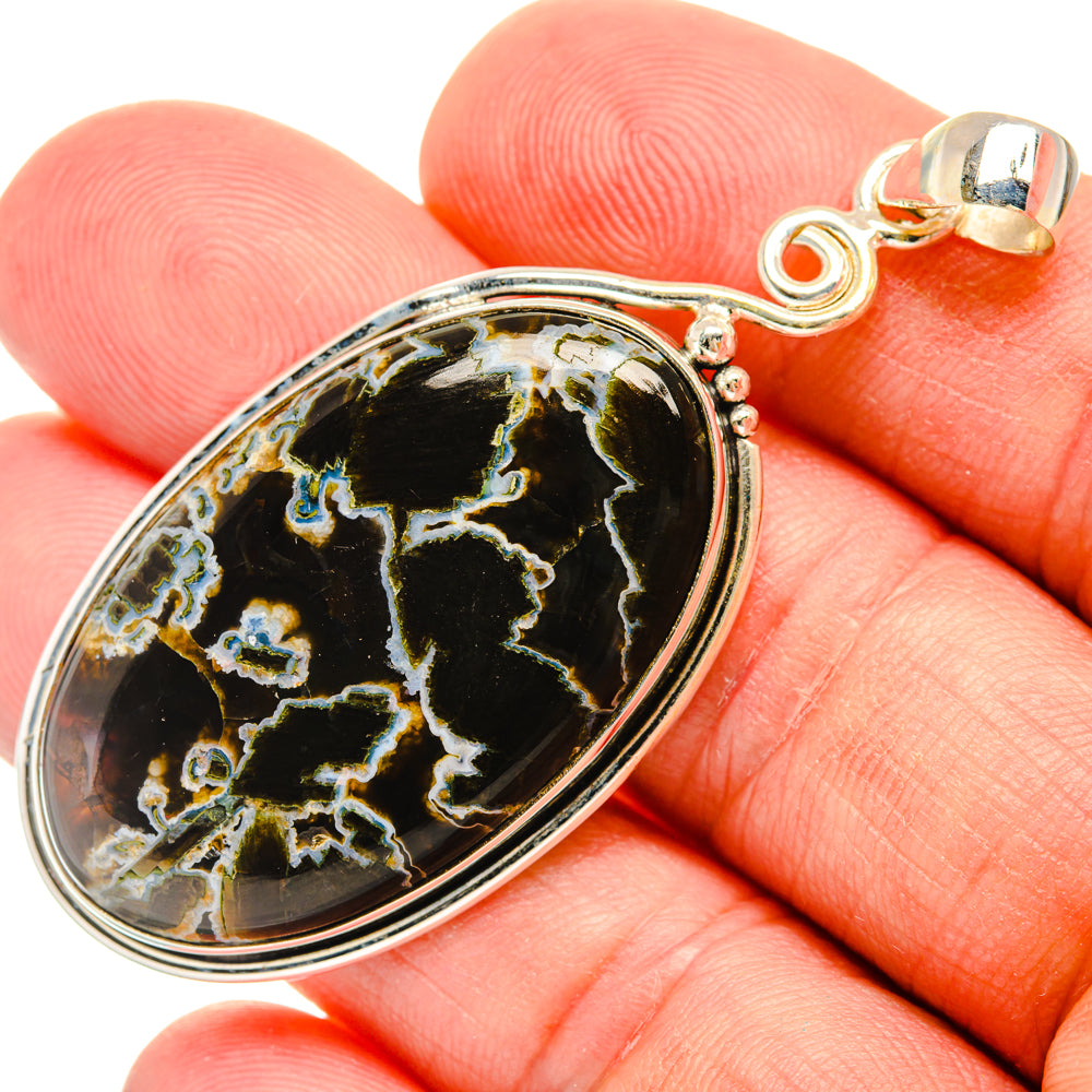 Oval black agate pendant in silver bezel with loop bail, detailed swirling gold color.