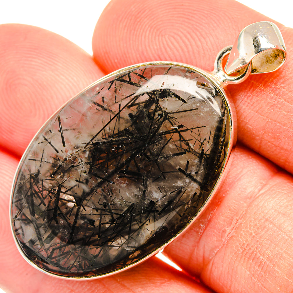 Silver bail tourmalinated quartz pendant, close-up oval stone with black needles.