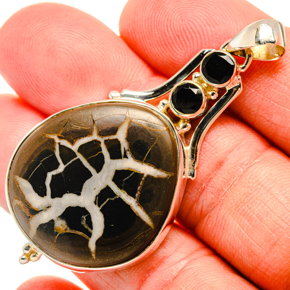 Septarian geode pendant in silver bezel with black cabochon accents
