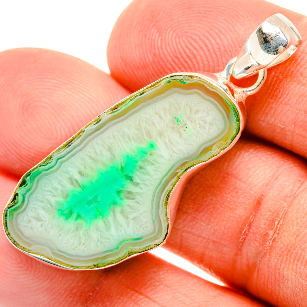 Green geode slice pendant with sterling silver bail, close-up on finger scale