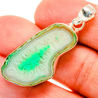 Green geode slice pendant with sterling silver bail, close-up on finger scale