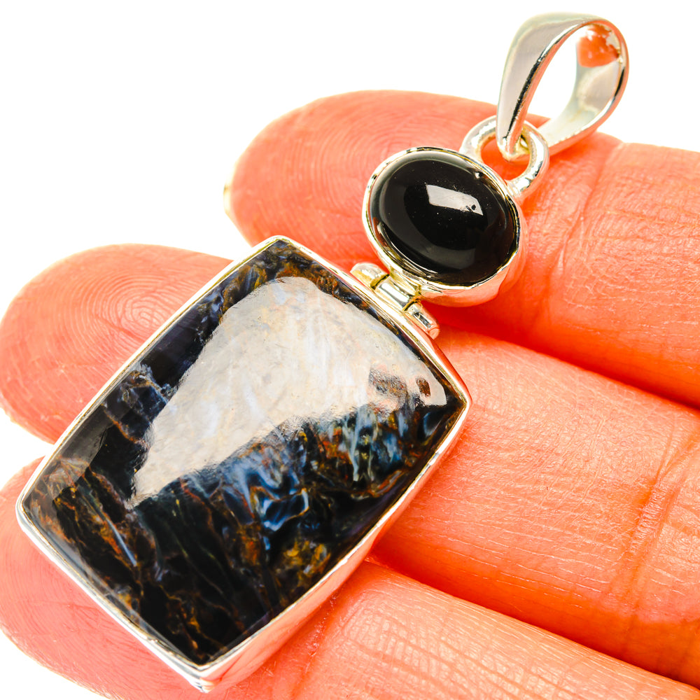Rectangle gemstone pendant with silver frame, black oval top, blue pietersite on hand