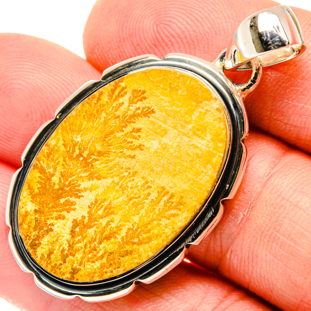 Oval dendrite pendant with yellow-orange cabochon, black rim, and silver bail