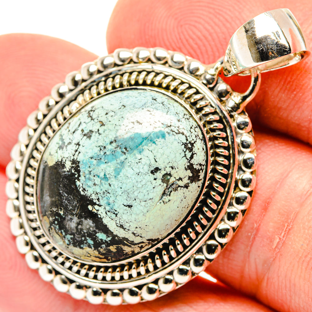 Round turquoise cabochon pendant in ornate sterling silver bezel, close-up view