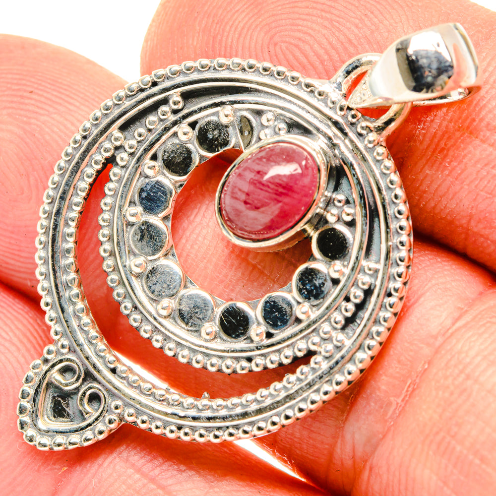 Sterling silver pendant close-up with pink-red cabochon and dark bezel accents