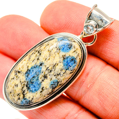 Oval sterling silver azurite pendant with blue stone bezel, close-up on fingers