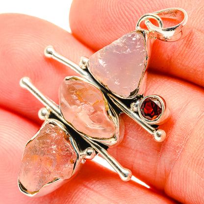 Sterling silver garnet and rough rose quartz pendant close-up on hand
