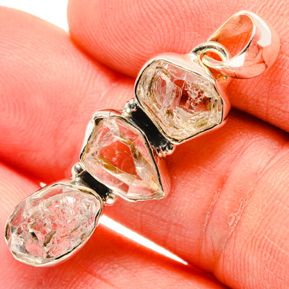 Clear faceted diamond pendant with three bezel-set stones on gold-tone mount, close-up