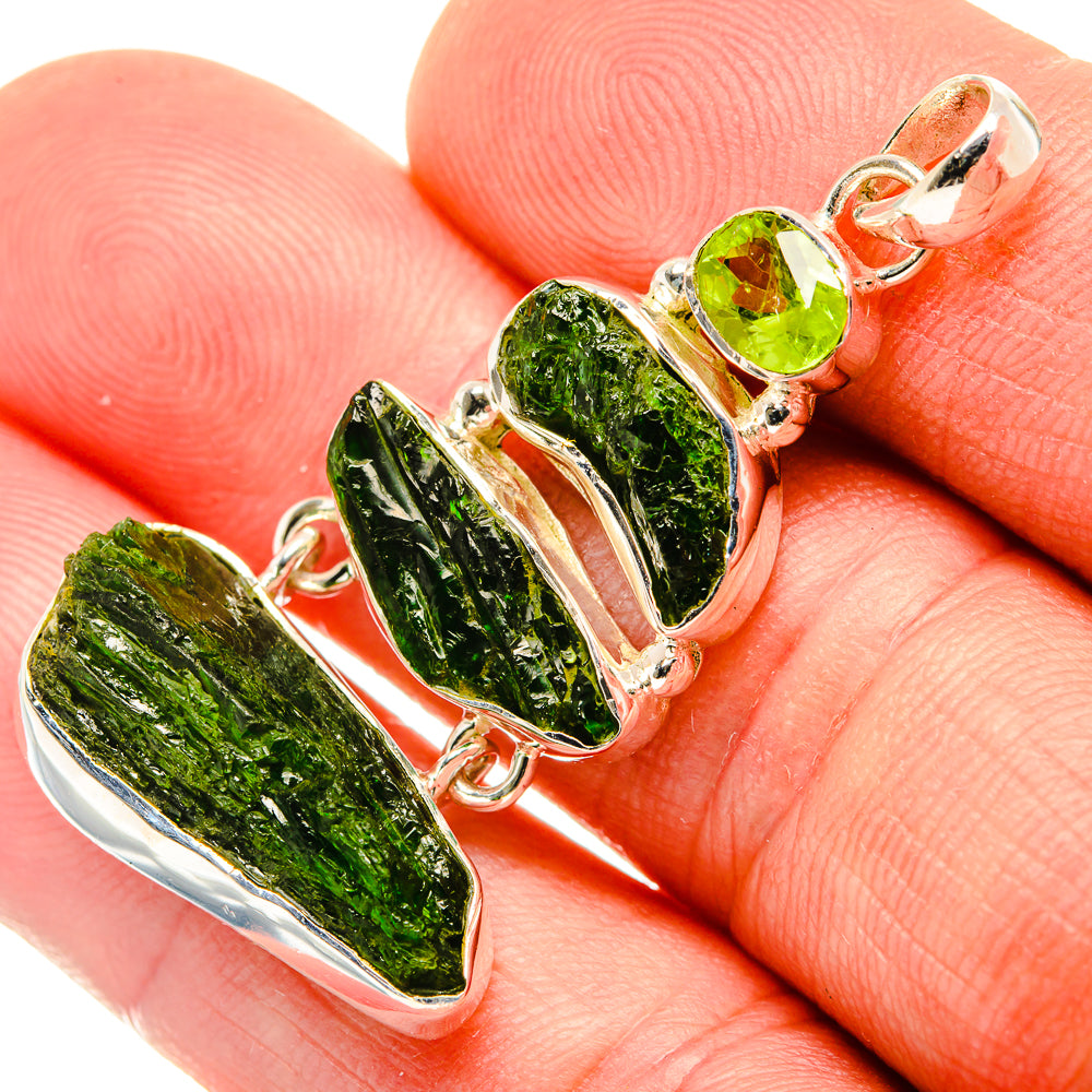 Rough green diopside pendant with round peridot stones in sterling silver, on hand