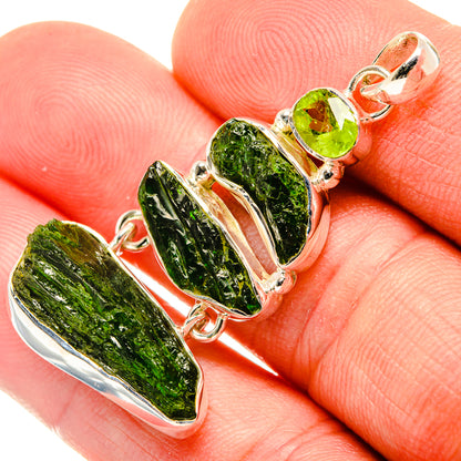 Rough green diopside pendant with round peridot stones in sterling silver, on hand